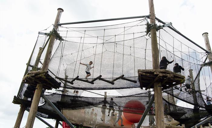 A huge adventure net with a netted trampoline in the centre